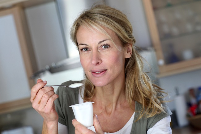 woman eating yogurt in kitchen